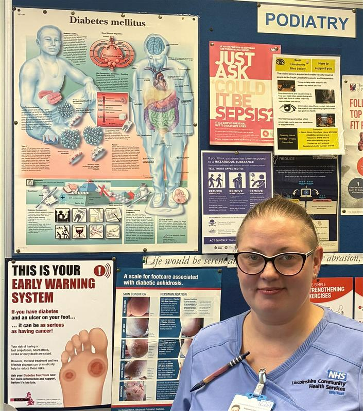 Image of Magdalena stood in front of a range of Podiatry posters
